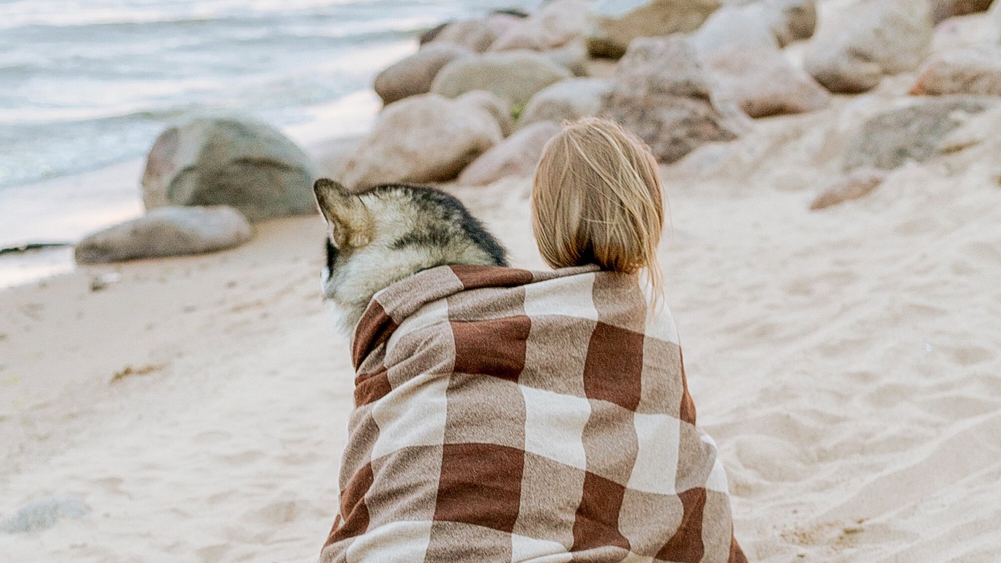 Owner and dog wrapped in a blanket enjoying the ocean views