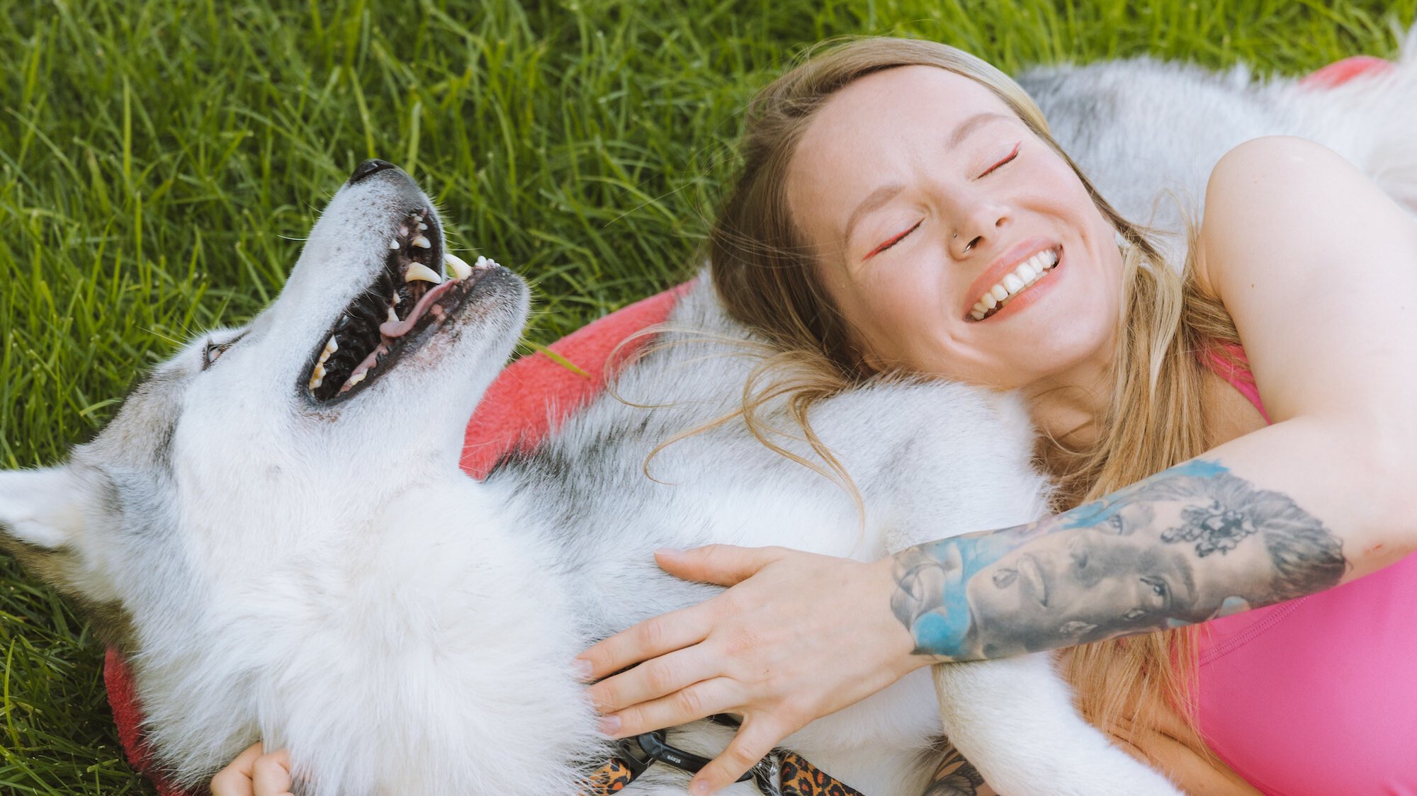 Owner & her dog happily laying in the grass together